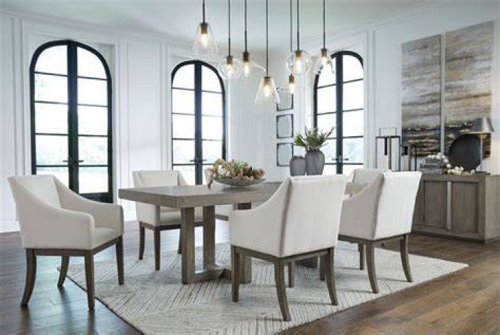 a dining room table with chairs and a bench in front of the window on a rug