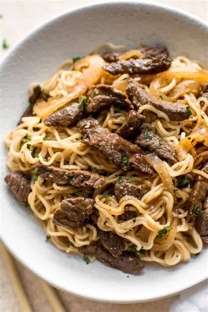 some noodles and meat are being cooked together